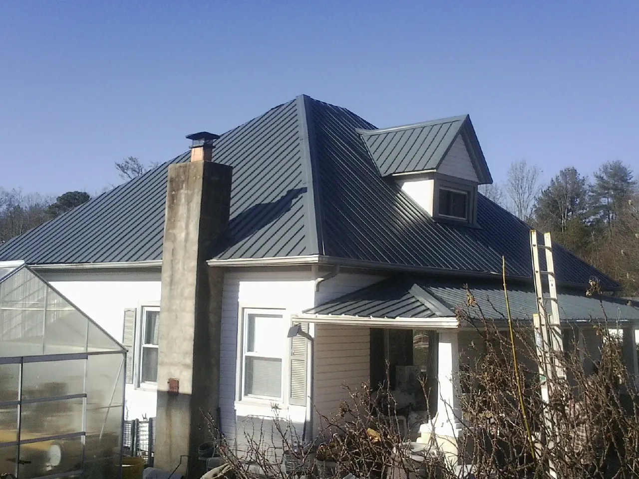 Dark blue standing seam metal roof on a white farmhouse with dormer — Slate & Tile Roof Repair by Roofing Brothers in Tiro