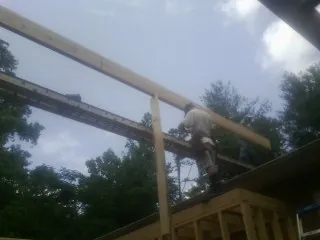 Carpenter setting a ridge beam over a new addition frame — Ice Dam Removal by Roofing Brothers in Tiro
