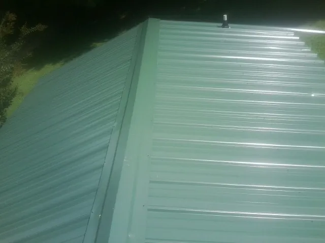 New green metal panels meeting at the ridge of a roof — Flat Roof Repair work by our crew in Tiro